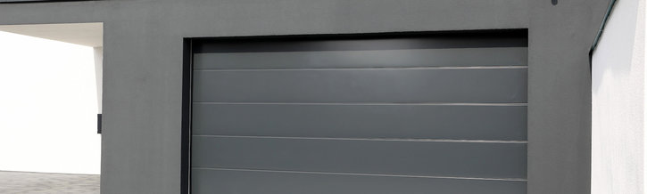 Ein graues, horizontal geriffeltes Garagentor mit einem kleinen Fenster oben, teilweise geöffnet und mit einem seitlichen Rahmen.