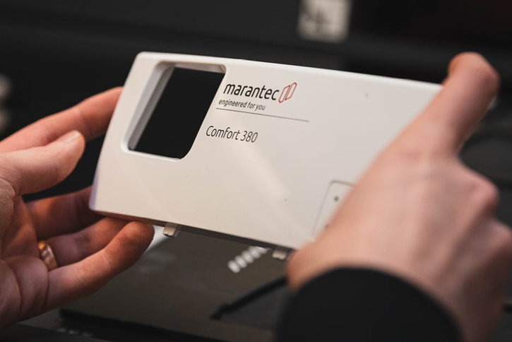 Eine Person hält das Frontteil des weißen Gehäuses eines Marantec Comfort 380 Garagentorantriebs in ihren Händen.