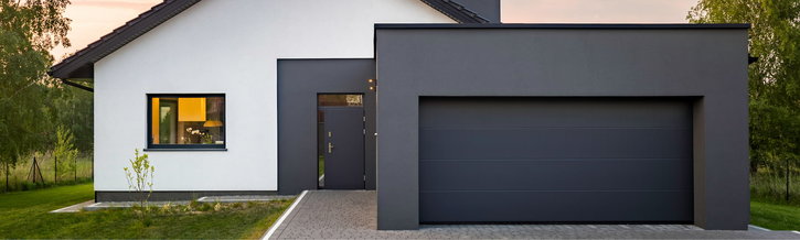 Ein modernes Haus mit einer grauen Garage und einem weißen Putz.