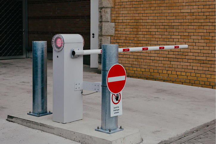 Eine automatische Schranke mit einem roten Licht und einem Stoppschild an einer Zufahrt.